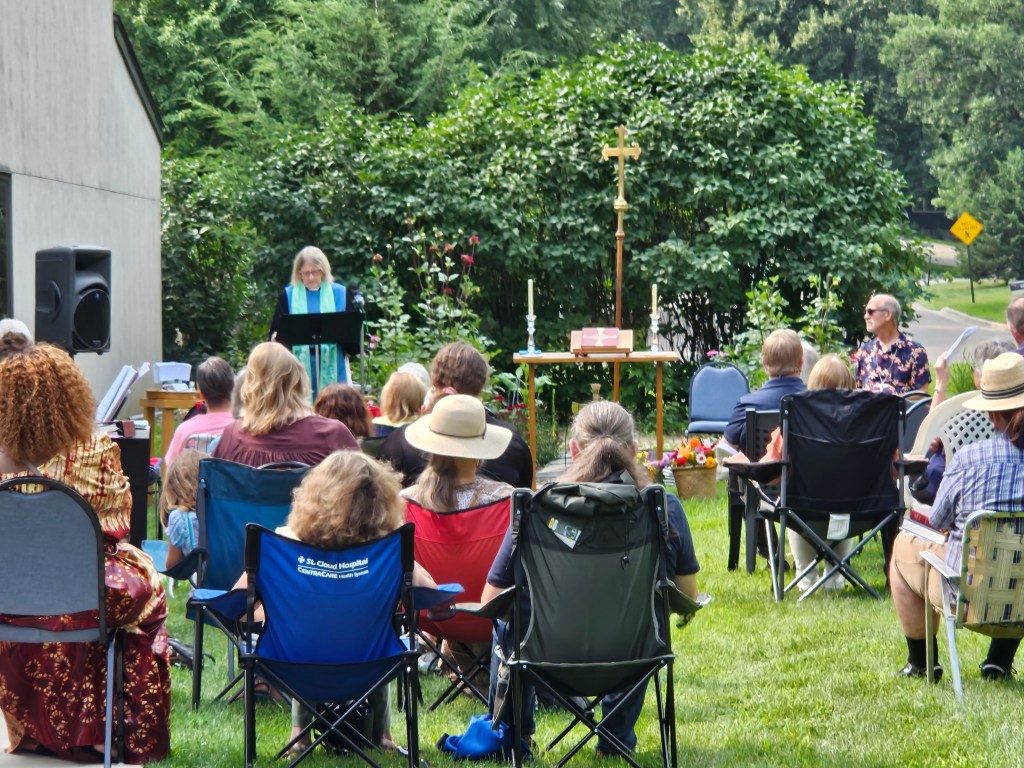 Outdoor church service in a lush garden.