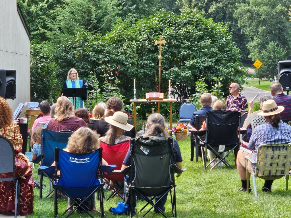 Outdoor church service in a lush garden.