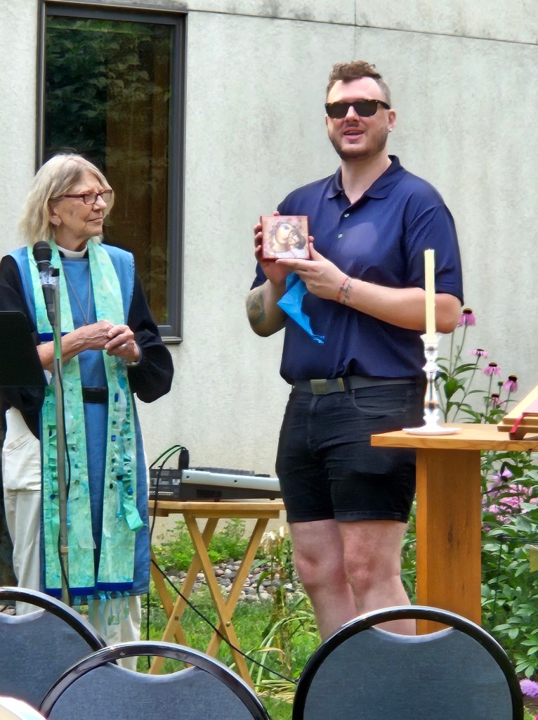 Church member displaying their new painting next to priest.