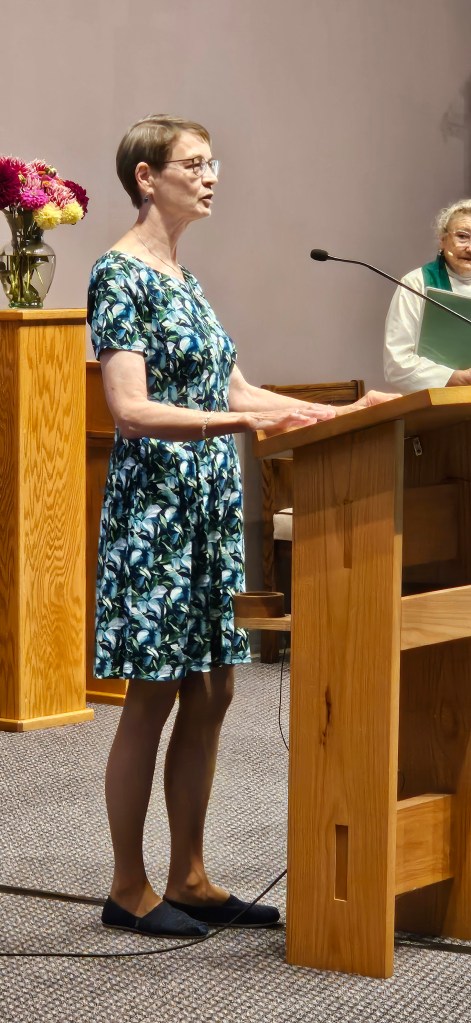 Friend of the church in blue dress speaking at altar.
