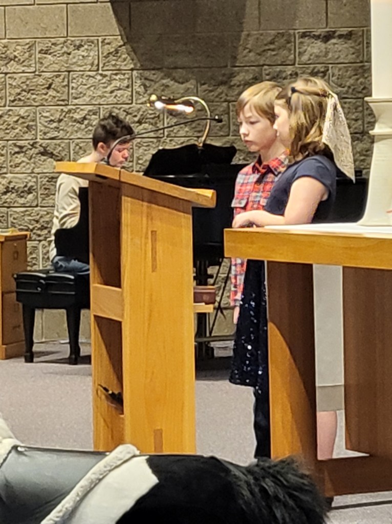 Two children at a podium narrating the Christmas pageant. 